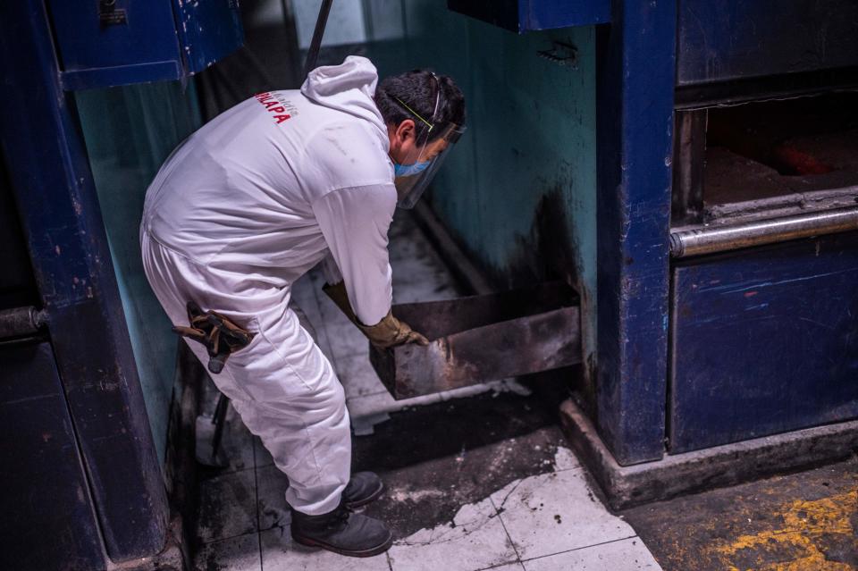 Un empleado de Iztapalapa saca las cenizas del cuerpo que acaban de incinerar del horno crematorio. Después habrá que meterlas en la urna. (Photo by PEDRO PARDO/AFP via Getty Images)