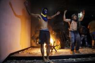 People chant slogans outside the Congress building during clashes between police and protesters opposing an approved proposed constitutional amendment that would allow the election of a president to a second term, in Asuncion, Paraguay, Friday, March 31, 2017. Some protesters broke through police lines and entered the first floor, where they set fire to papers and furniture. Police used water cannon and fired rubber bullets to drive demonstrators away from the building while firefighters extinguished blazes inside. (AP Photo/Jorge Saenz)