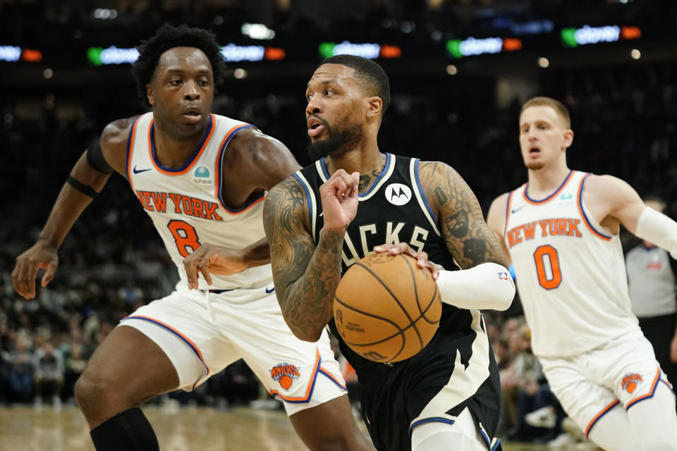 Milwaukee Bucks' Damian Lillard, center, drives to the basket between New York Knicks' OG Anunoby, left, and Donte DiVincenzo, right, during the second half of an NBA basketball game Sunday, April 7, 2024, in Milwaukee. (AP Photo/Aaron Gash)