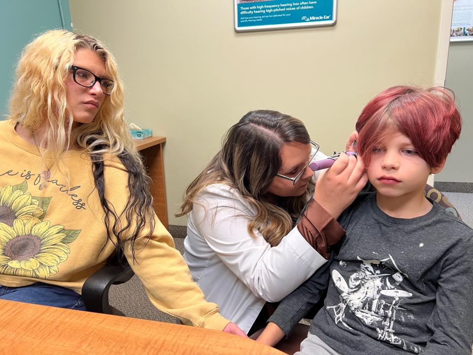 Shalynn McCafferty (left) looks on as Miracle Ear hearing specialist Alexia Malone fits McCafferty's son, Lance "Treigh" Mullins with two hearing aids. The Pleasantville Elementary School third-grader suffers from hearing loss in both ears due to inner ear nerve damage.