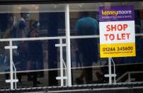 FILE PHOTO: Shoppers are reflected in the window of a closed shop following the outbreak of the coronavirus disease (COVID-19) in Chester, Britain