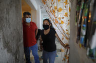 Jose Juan Serralde and his wife Blanca Evangelista Villada walk into their home's front hall in San Gregorio Atlapulco, Xochimilco, Mexico City, Wednesday, July 29, 2020, after his parents died of COVID-19 in May while living with them. Serralde wasn’t sure how to implement health officials’ recommendations until a friend who is a doctor explained after his father died that the family should use disposable plates and plasticware, clean the bathroom with bleach after each person used it, and get everyone in the house, except his youngest daughter, tested. (AP Photo/Rebecca Blackwell)