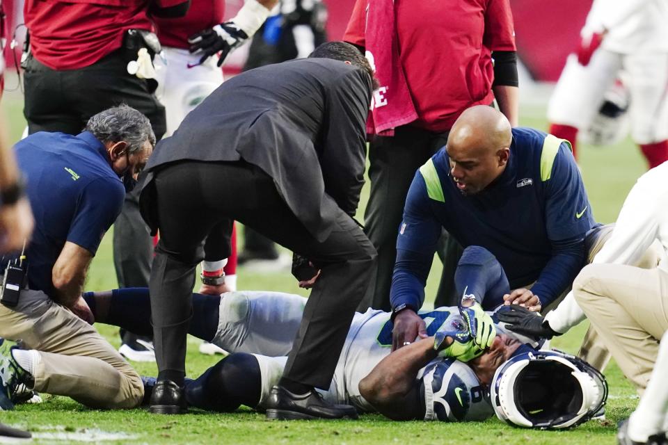 An injured Seattle Seahawks free safety Quandre Diggs grimaces as he is attended to by Seahawks training and medical staff during the second half of an NFL football game against the Arizona Cardinals Sunday, Jan. 9, 2022, in Glendale, Ariz. (AP Photo/Darryl Webb)