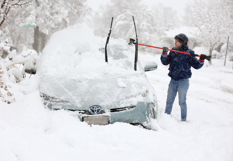 Cathy Morgan-Mace cleans snow and ice off her family’s car during a snowstorm in Salt Lake City, on Feb. 22, 2023.