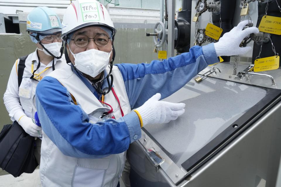 This photo taken during the tour of the treated water dilution and discharge facility for foreign media shows TEPCO official Kenichi Takahara explains about a facility to take samples of treated radioactive wastewater after dilution for testing before release, part of the facility for the releasing treated radioactive water to sea from the Fukushima Daiichi nuclear power plant, operated by Tokyo Electric Power Company Holdings (TEPCO), in Futaba town, northeastern Japan, Sunday, Aug. 27, 2023. (AP Photo/Eugene Hoshiko, Pool)