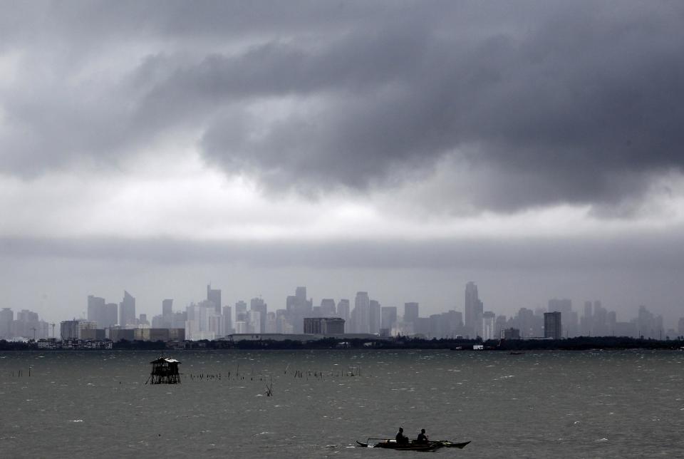 Fishermen ride on their boat as dark clouds loom over the city brought by Typhoon Usagi in Manila