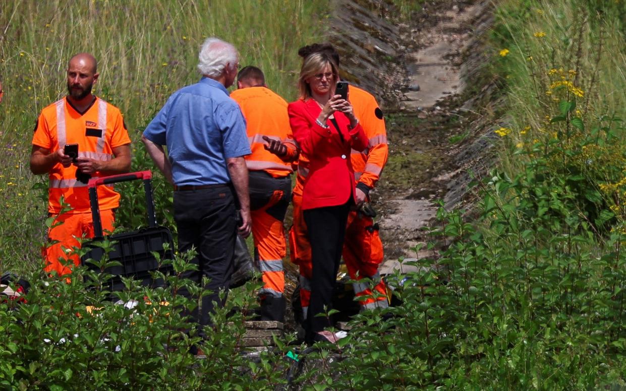 Ms Pannier-Runacher stands with men in hi-vis suits on a railway line