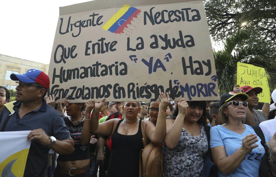 FILE - In this Feb. 12, 2019 file photo, Venezuelans living in Colombia protest the government of Venezuela's President Nicolas Maduro, and its blocking the entry of humanitarian aid, in Cucuta, Colombia, on the border with Venezuela. The sign reads in Spanish "Urgent. The entry of humanitarian help is needed now. There are Venezuelans at risk of dying." (AP Photo/Fernando Vergara, File)