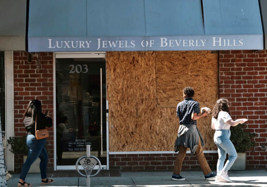 Pedestrians walk past a boarded up Luxury Jewels of Beverly Hills on Wednesday, March 23, 2022 in Beverly Hills, Calif. (AP Photo/Richard Vogel)
