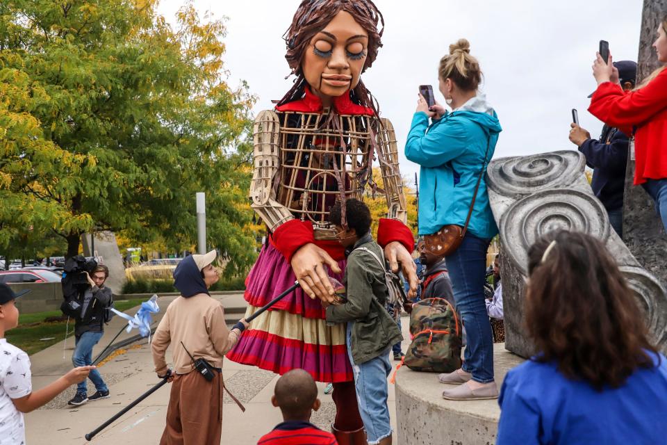 Little Amal, a 12-foot-tall puppet of a 10-year-old Syrian refugee girl, gives Daria Nimbee, 26, of Detroit a hug during a live art performance at the Bagley Pedestrian Bridge, in Southwest Detroit on Wednesday, Sept. 27, 2023. The U.S. tour began in Boston on Sept. 7 and will conclude in San Diego on Nov. 5.