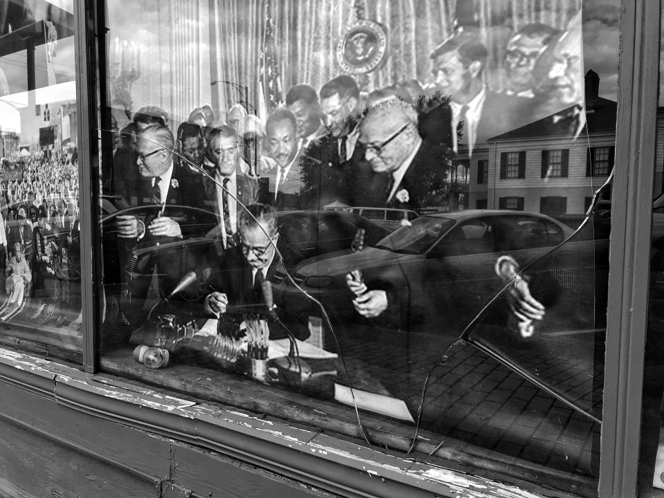 <p>A 1965 photo of Martin Luther King Jr and other leaders behind President Lyndon B. Johnson as he signed the 1965 Voting Rights Act is displayed behind a shattered window in downtown Selma, Ala. (Photo: Holly Bailey/Yahoo News) </p>