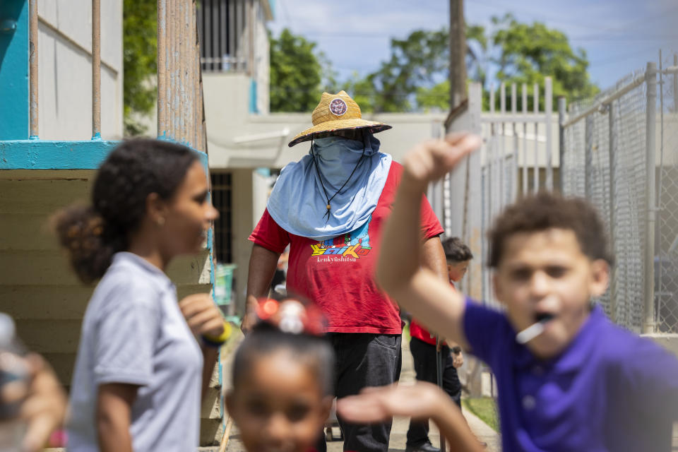 A school maintenance worker wears sun protection at the Escuela Elemental Santiago Iglesias Pantín school in San Juan, Puerto Rico, Thursday, Sept. 7, 2023. Students and teachers are holding class in public schools across Puerto Rico that lack air conditioning amid record heat this year. (AP Photo/Alejandro Granadillo)