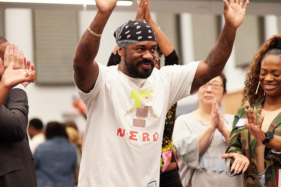 JaQuel Knight raises both hands and smiles as a group around him applauds.