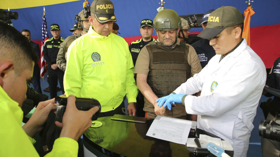 In this photo released by the Colombian Presidential Press Office, police fingerprint Dairo Antonio Usuga, also known as "Otoniel," leader of the violent Clan del Golfo cartel prior to his extradition to the U.S., at a military airport in Bogota, Colombia, Wednesday, May 4, 2022. (Colombian presidential press office via AP)