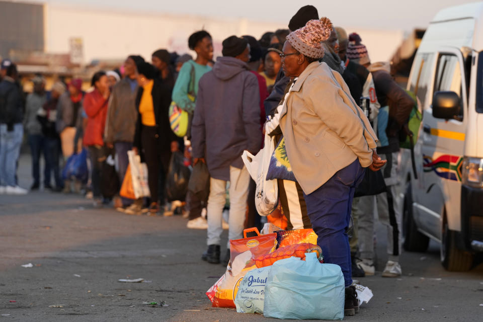 Commuters queuing to catch minibus taxi in Welkom, South Africa, Friday, June 23, 2023. At least 31 people were believed to have died in a gas explosion in a disused mine shaft in South Africa that happened last month but was only now coming to light, authorities said Friday. (AP Photo/Themba Hadebe)