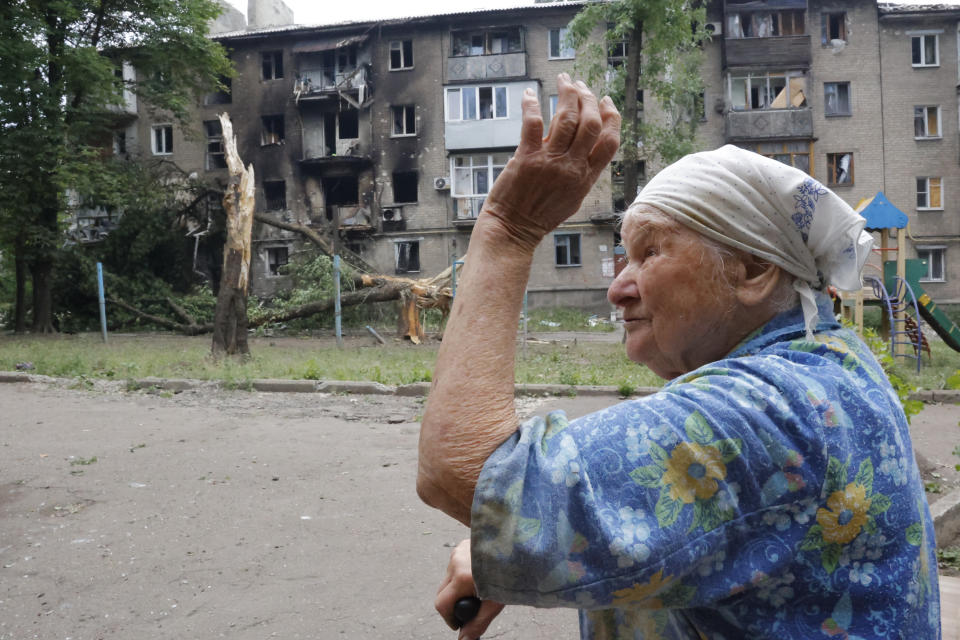 A woman gestures near an apartment building damaged during shelling in Donetsk, in territory under the government of the Donetsk People's Republic, eastern Ukraine, Wednesday, June 22, 2022. (AP Photo/Alexei Alexandrov)