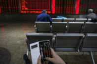 A man checks stock prices through his smartphone at a brokerage house in Beijing, Tuesday, Jan. 22, 2019. Asian markets were mostly lower on Tuesday after the International Monetary Fund trimmed its global outlook for 2019 and 2020. This came after China said its economy grew at the slowest pace in 30 years. (AP Photo/Andy Wong)