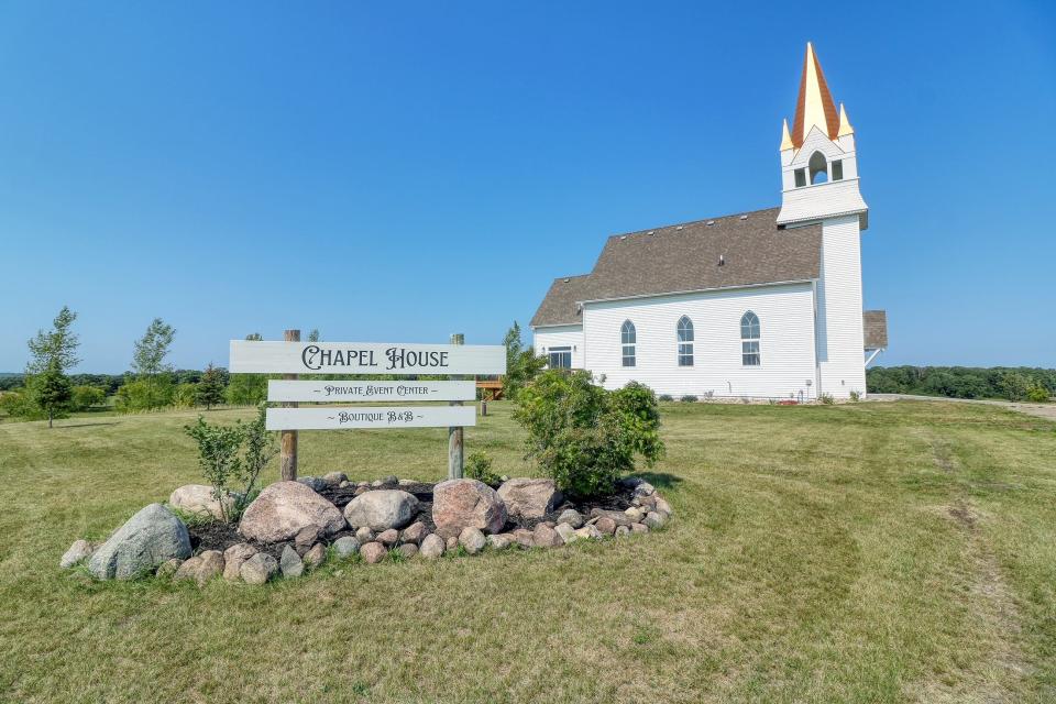 A white chapel with a gold steeple with a sign posted outside indicating its an event center and an Airbnb.