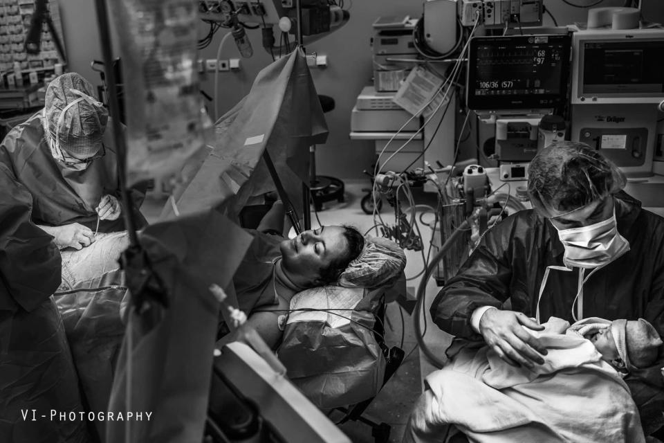 Mother in a birthing room with medical staff and newborn