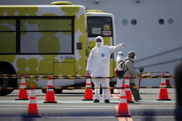 A passenger is directed in a car park after disembarking from the quarantined Diamond Princess cruise ship in Yokohama, near Tokyo