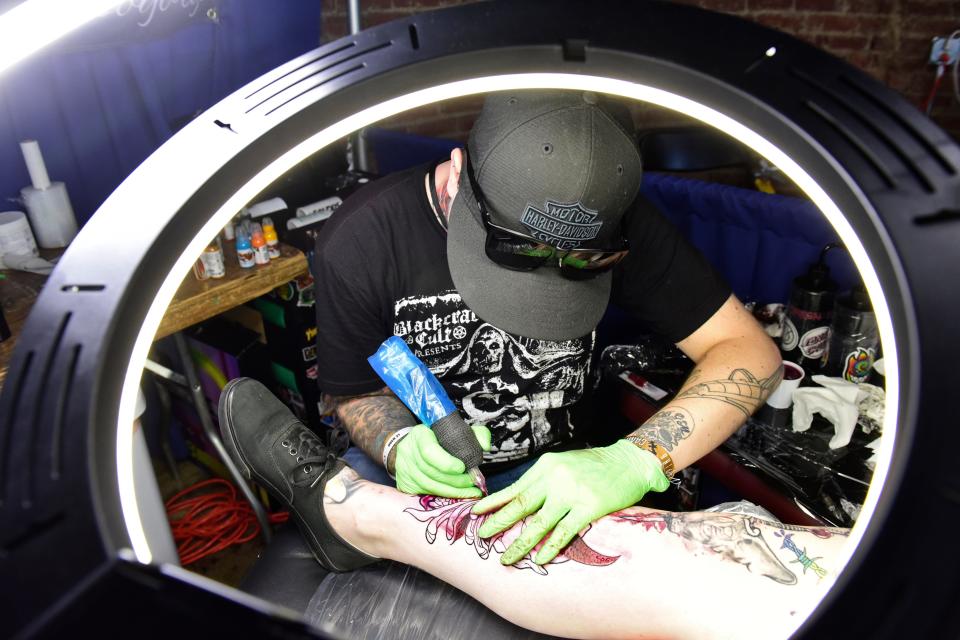 Bryer Heath, a tattoo artist from Davenport, Iowa, uses a ring light while working on a tattoo during the 2023 INKcarceration Music & Tattoo Festival.
