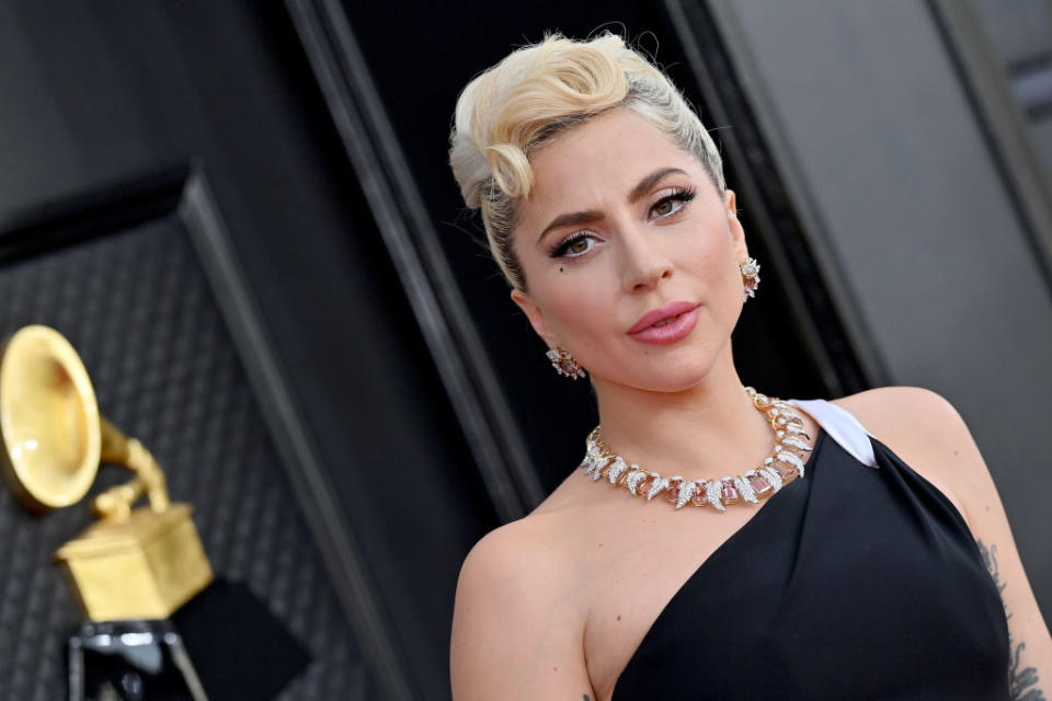 Lady Gaga on the red carpet wearing an elegant, off-shoulder gown and a statement necklace at a Grammy Awards event