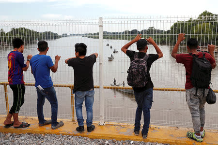 Men, part of a caravan of thousands of migrants from Central America en route to the U.S., look at the Mexican marine army patrolling the Suchiate River as they try to cross into Mexico and carry on their journey, in Tecun Uman, Guatemala, October 28, 2018. REUTERS/Carlos Garcia Rawlins