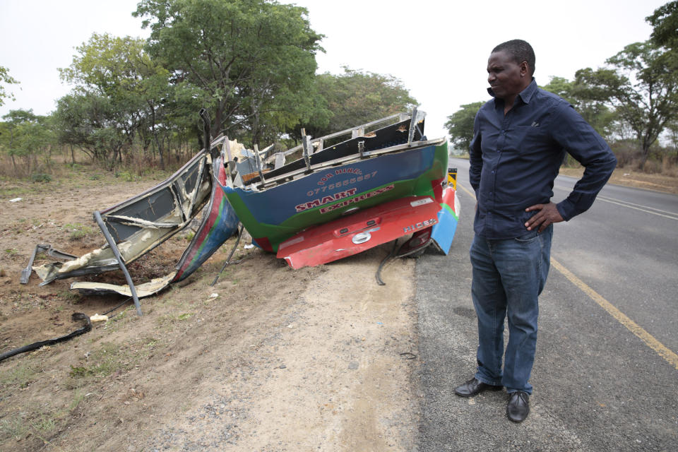 A man stands at the scene of a bus crash in Rusape about 170 kilomertes east of the capital Harare, Thursday, Nov. 8, 2018. A head-on collision between two buses has killed 47 people, where road accidents are common due to poor roads and bad driving. (AP Photo/Tsvangirayi Mukwazhi)