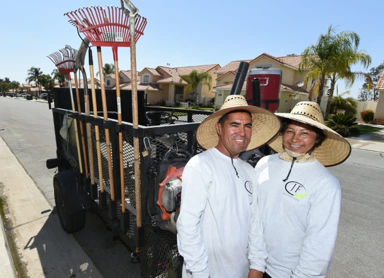 Jaime Flores (L) and his wife Ana Flores (R), migrants from Mexico who came to the United Sates 27 years ago, pose for a photo while doing landscape maintenance work, in Perris, California