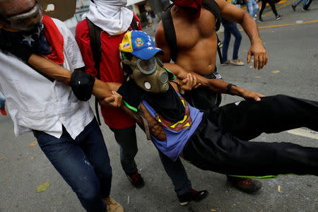 An injured opposition supporter is helped during a rally against Venezuela's President Nicolas Maduro in Caracas, Venezuela, May 1, 2017. REUTERS/Carlos Garcia Rawlins