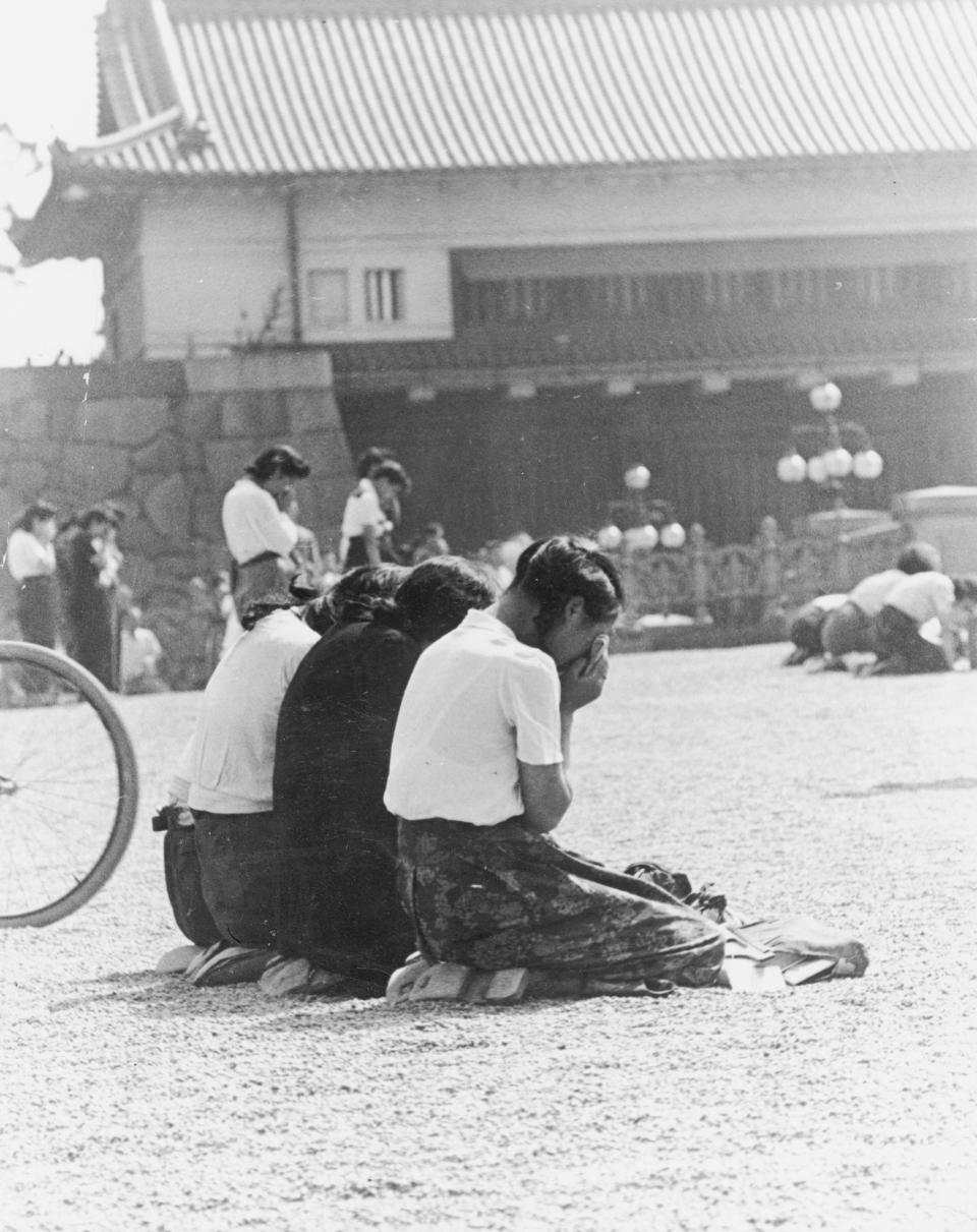 FILE - In this August, 1945, file photo, three Japanese schoolgirls weep in front of Japanese Emperor Hirohito's palace in Tokyo. Emperor Hirohito, the grandfather of current Emperor Naruhito, announced Japan's surrender in a prerecorded radio message on Aug. 15, 1945. It was the first time most Japanese had heard the voice of the emperor, who had been revered as a god, though it was muffled and nearly inaudible due to poor sound quality. (AP Photo, File)