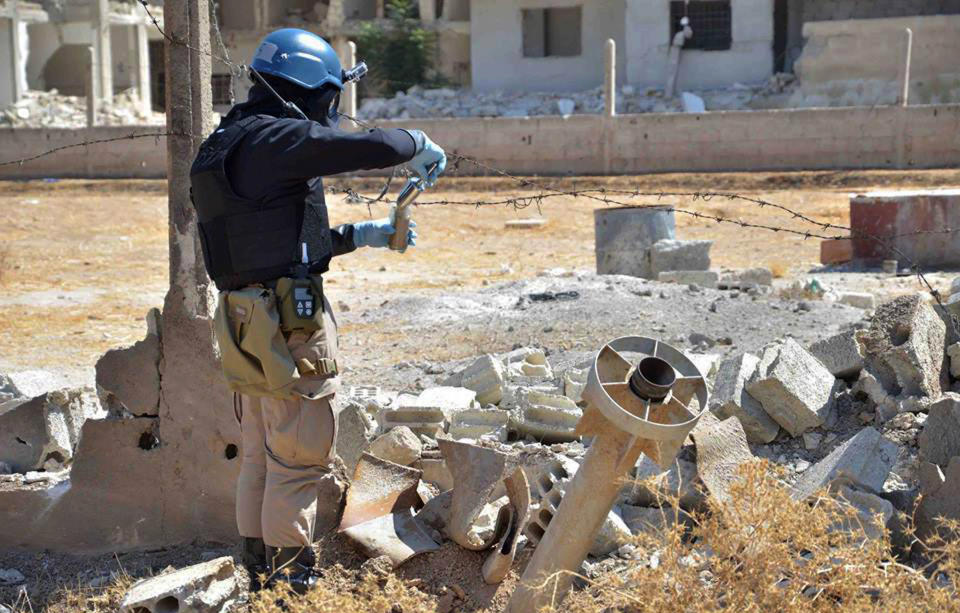 FILE - This Wednesday, Aug. 28, 2013 citizen journalism file image provided by the United media office of Arbeen which has been authenticated based on its contents and other AP reporting, shows a member of UN investigation team taking samples of sands near a part of a missile that is likely to be one of the chemical rockets according to activists, in Damascus countryside of Ain Terma, Syria. On Saturday, April 12, 2014 the Syrian government and rebel forces say poison gas has been used in a central village, injuring scores of people, while blaming each other for the attack. The main Western-backed opposition group, the Syrian National Coalition, says dozens of people were hurt in a poison gas attack Friday in the village of Kfar Zeita. State-run Syrian television on Saturday blamed members of the al-Qaida-linked Nusra Front for using chlorine gas at Kfar Zeita, killing two people and injuring more than 100. (AP Photo/United media office of Arbeen, File)