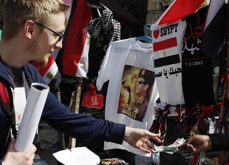 A tourist buys a poster of Egypt's army chief, Field Marshal Abdel Fattah al-Sisi, who is also pictured on a shirt, at a vendor in Tahrir square in Cairo February 22, 2014. REUTERS/Asmaa Waguih