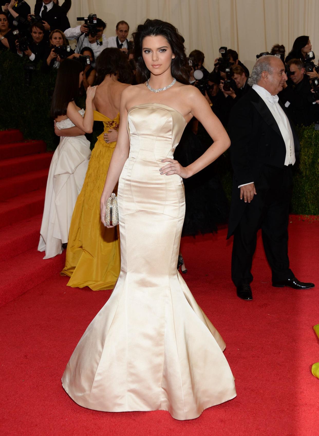 Kendall Jenner attends the 2014 Met Gala in a cream colored gown with a trumpet skirt.
