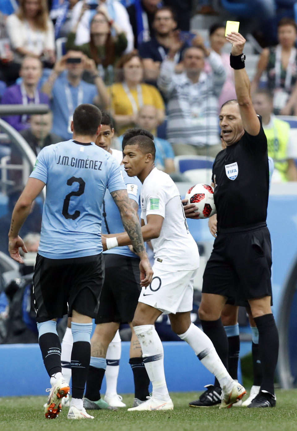 France’s Kylian Mbappe, center, receives a yellow card by referee Nestor Pitana during the quarterfinal match between Uruguay and France at the 2018 soccer World Cup in the Nizhny Novgorod Stadium, in Nizhny Novgorod, Russia, Friday, July 6, 2018. (AP Photo/David Vincent)
