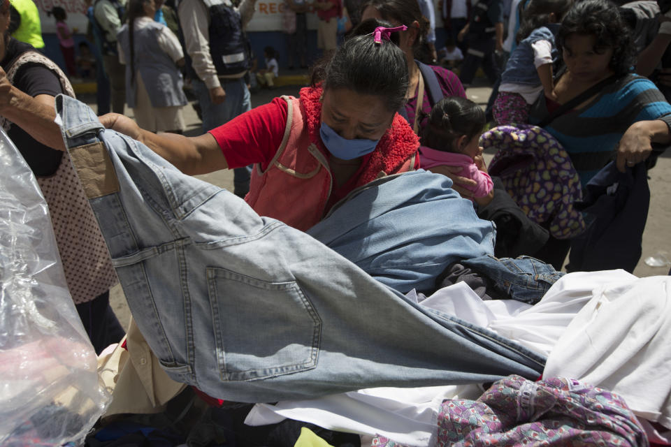 A woman goes through a pile of donated clothes, outside a shelter in San Gregorio Atlapulco, Mexico, Friday, Sept. 22, 2017. Mexican officials are promising to keep up the search for survivors as rescue operations stretch into a fourth day following Tuesday’s major earthquake that devastated Mexico City and nearby states. (AP Photo/Moises Castillo)