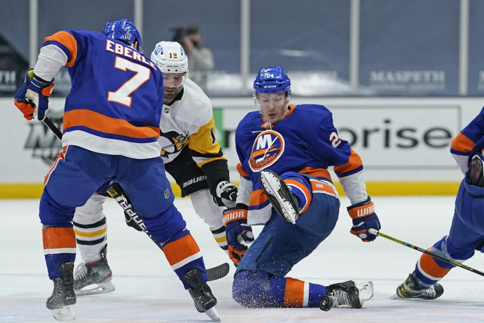 New York Islanders defenseman Scott Mayfield (24) slips in front of Pittsburgh Penguins center Zach Aston-Reese (12) and Islanders right wing Jordan Eberle (7) during the second period of an NHL hockey game, Sunday, Feb. 28, 2021, in Uniondale, N.Y. (AP Photo/Kathy Willens)