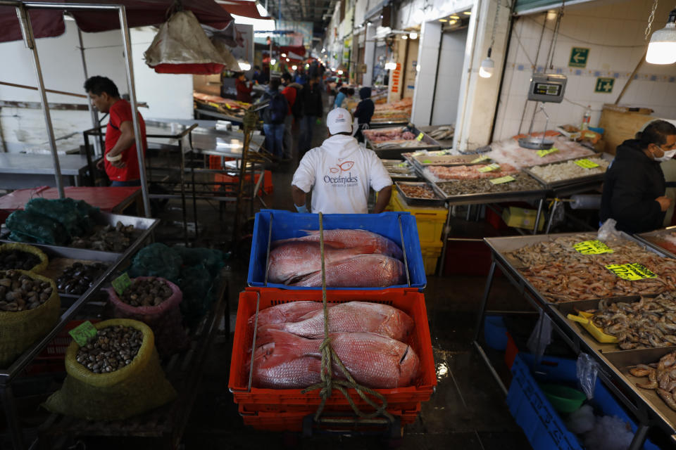 A worker pulls a cart with an order of red snapper for a client at the La Nueva Viga seafood market, part of the Central de Abastos, the capital's main market, in Mexico City, Wednesday, Dec. 9, 2020, amid the new coronavirus pandemic. With numbers of reported COVID-19 infections on the rise, shoppers and sellers worry how increased restrictions will affect their businesses during this year’s holiday season. (AP Photo/Rebecca Blackwell)