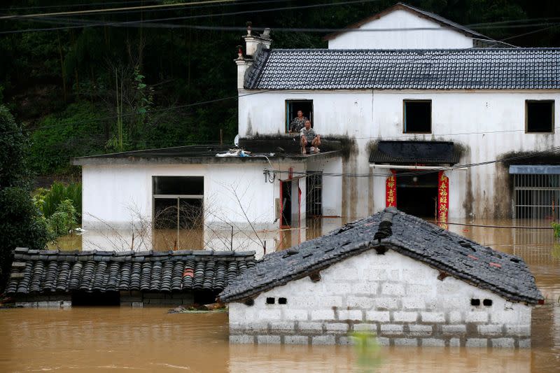 People look on from a house in a flooded village following heavy rainfall in Huangshan, Anhui province