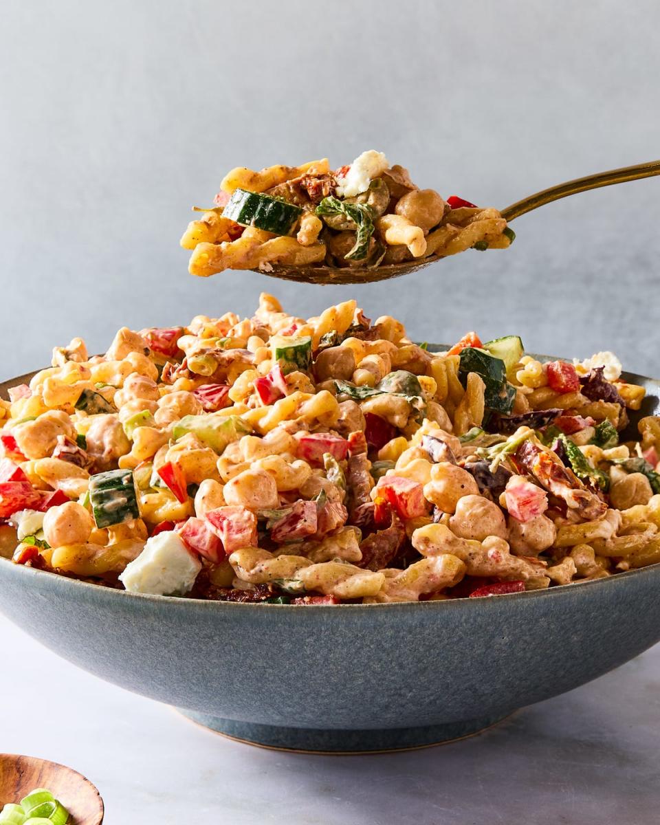 gemelli pasta tossed with chickpeas, bell pepper, cucumber, scallions, feta, olives, herbs, and tomatoes, then tossed in harissa mayo