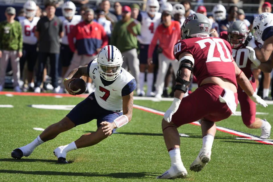 Arizona quarterback Jayden de Laura tries to avoid Washington State defensive end Quinn Roff (20) in the first half during an NCAA college football game, Saturday, Nov. 19, 2022, in Tucson, Ariz. (AP Photo/Rick Scuteri)