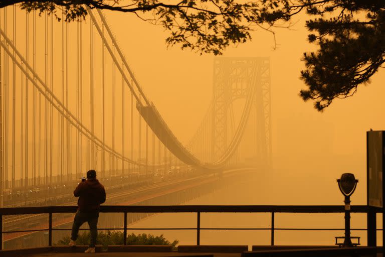 Un hombre conversa por su teléfono en medio de una bruma de humo de los incendios forestales cerca del puente George Washington, en esta imagen tomada desde Fort lee, Nueva Jersey, el miércoles 7 de junio de 2023. 