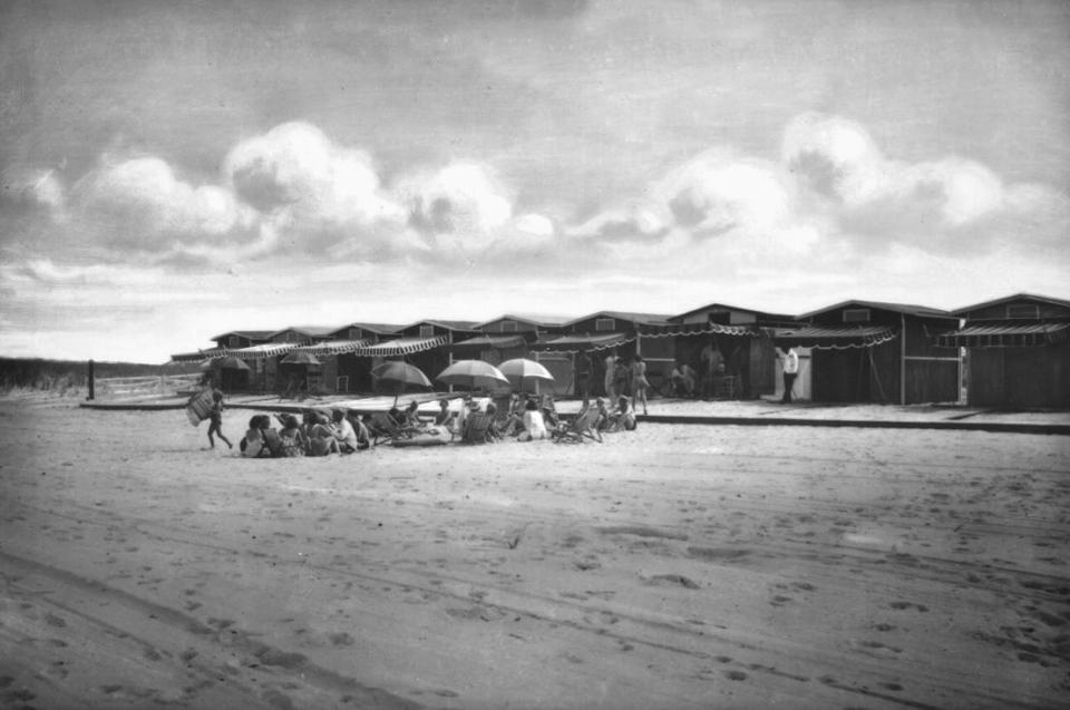 A line of cabanas and a gathering of sunbathers along the beach in Fenwick Island. Through the 1950s, Fenwick Island remained almost undeveloped.
