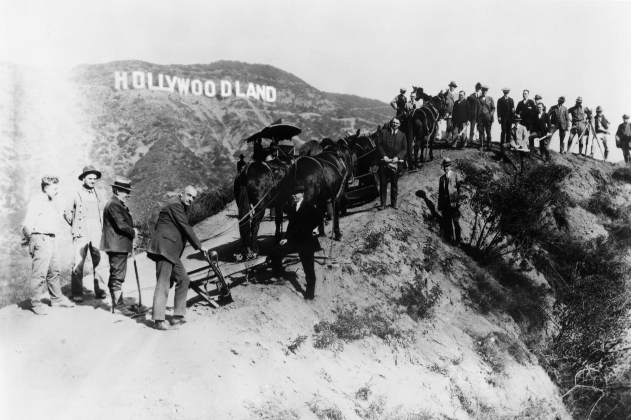 A group of men most likely surveyors and builders working on the new housing developement known as Hollywoodland pose for a portrait beneath the sign that was erected to advertize the site, circa 1925 in Los Angeles, California