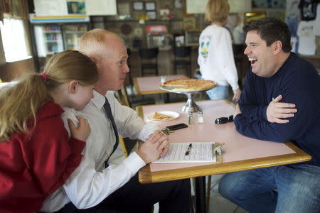 James Keady (C), who is running as a Democrat for New Jersey Assembly, is hugged by his six-year-old daughter Reese (L), while petitioning for signatures from John Doughterty, at Don's Pizza King Restaurant in Belmar, New Jersey March 28, 2015. REUTERS/Mark Makela
