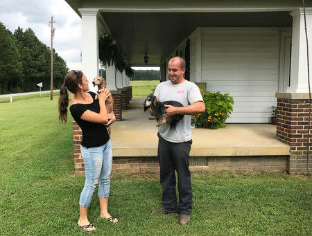 Bradley Dixon and his girlfriend Emily Mason hold their two dachshunds outside his home near Alamance County in Mebane, North Carolina, U.S., August 24, 2017. REUTERS/Colleen Jenkins