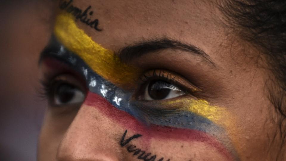 Imagen muy cerrada de los ojos de una mujer con la bandera colombiana y venezolana pintada en el rostro y las palabras &quot;Colombia&quot; y &quot;Venezuela&quot;.