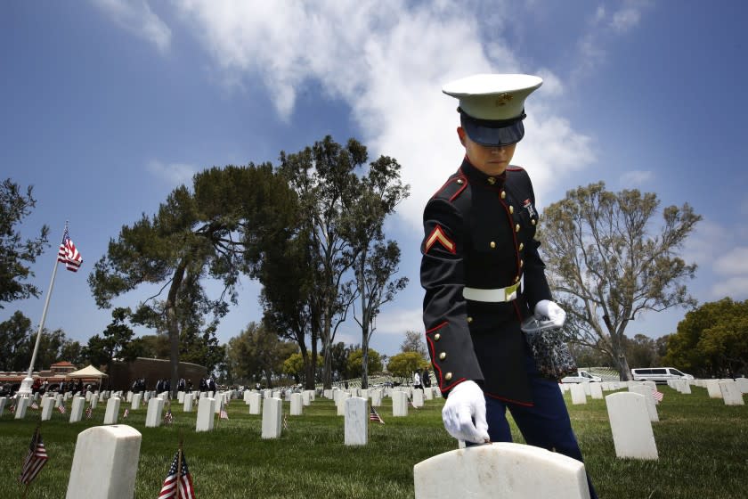 As a show of respect, Marine Pfc. Morgan Weibel places a penny for the fallen during a Memorial Day celebration at the Los Angeles National Cemetery.