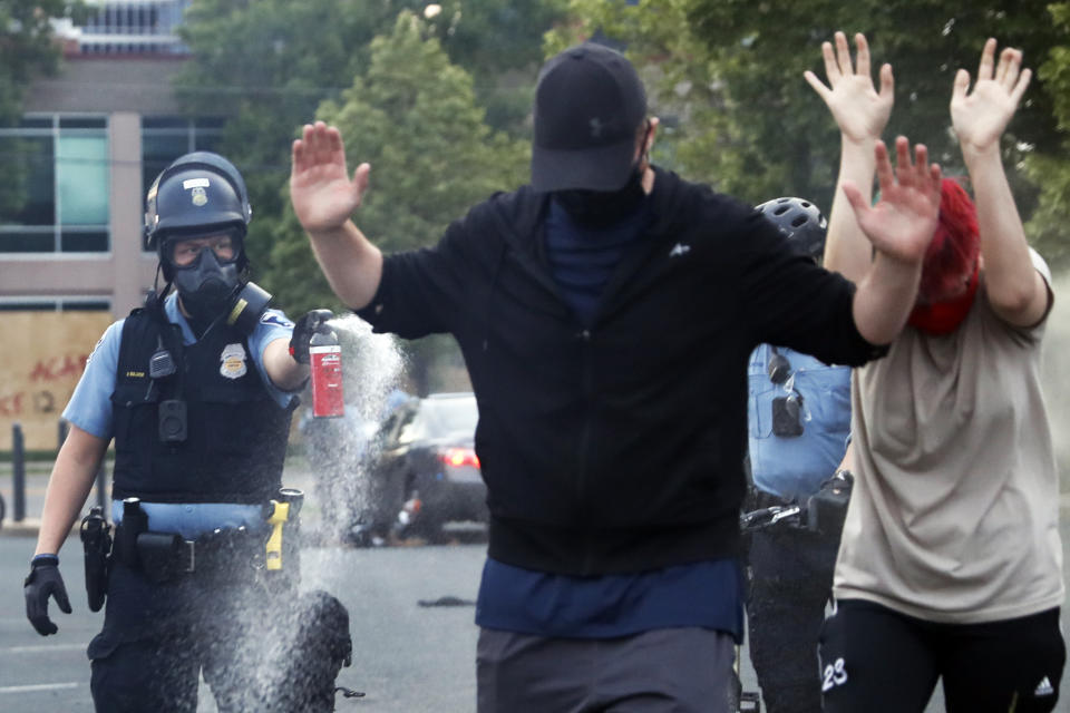 An officer points pepper spray towards people after curfew on Sunday, May 31, 2020 in Minneapolis. Protests continued following the death of George Floyd, who died after being restrained by Minneapolis police officers on Memorial Day. (AP Photo/John Minchillo)