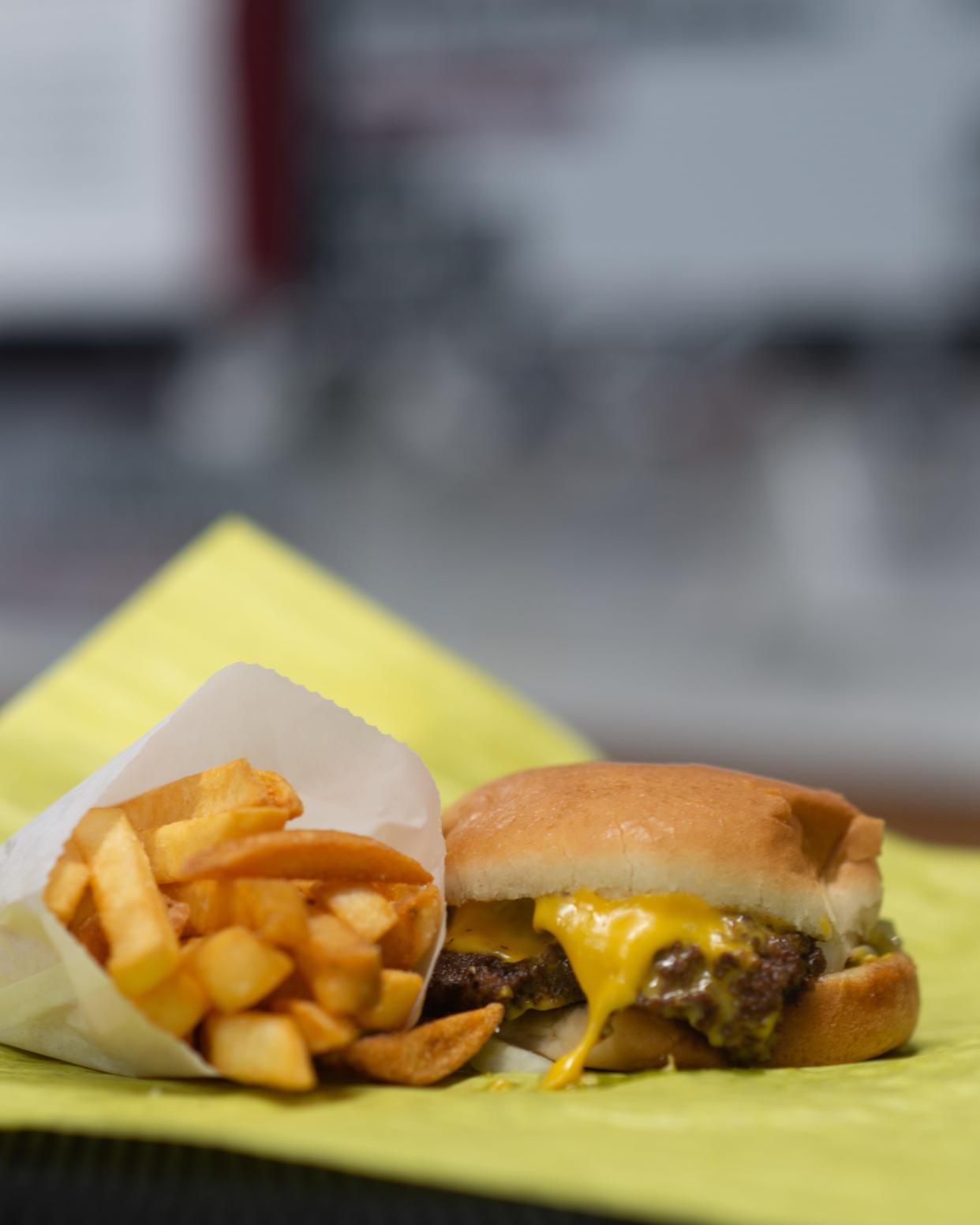 Melted cheese oozes out of a double cheeseburger from Harold's Prize Package on Friday afternoon as seen in an order with French fries.